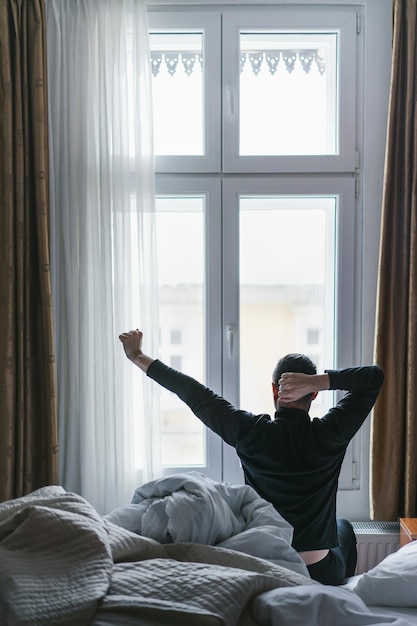 young man sitting on bed at home