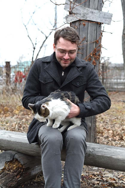 Young man sitting on a bench and petting a cat