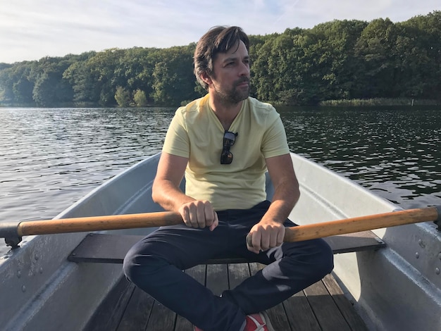 Young man sitting on boat against lake