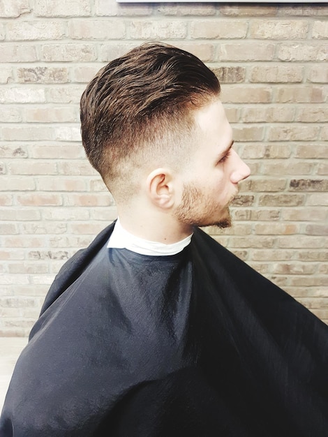 Photo young man sitting by brick wall at salon