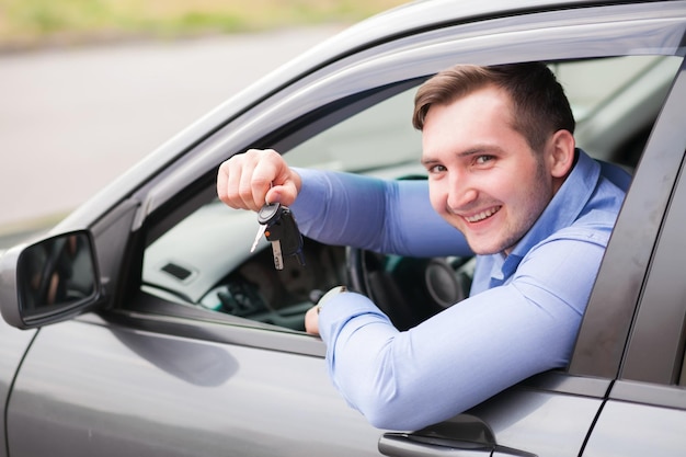 車のキーを保持している車に座っている若い男