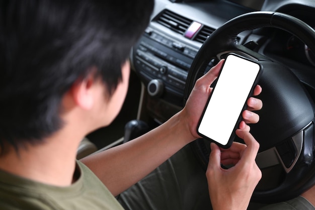 Young man sitting in a car and using mobile phone