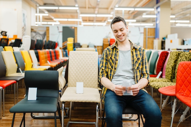 Young man sitting on chair in furniture store showroom.