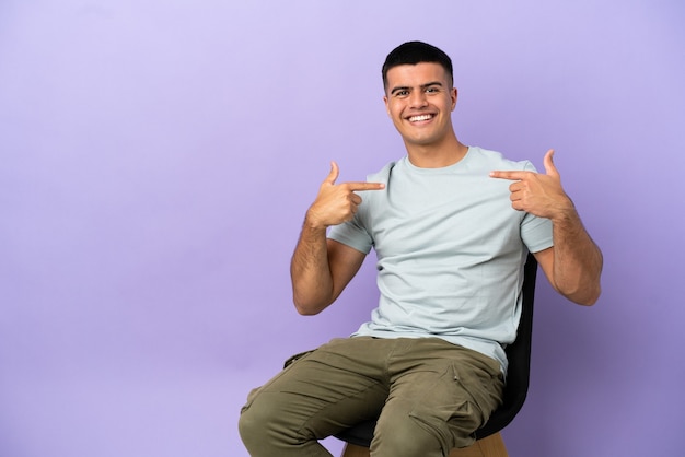 Young man sitting on a chair over isolated background proud and self-satisfied