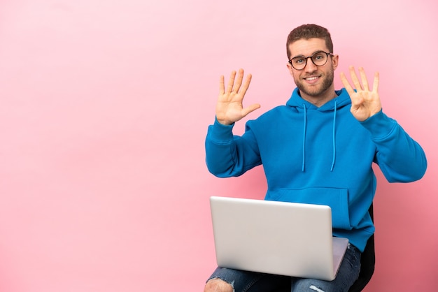 Young man sitting on a chair with laptop counting nine with fingers