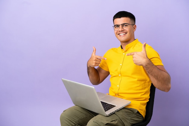 Young man sitting on a chair with laptop proud and self-satisfied