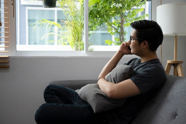 Young man sitting on comfortable sofa and talking on mobile phone.