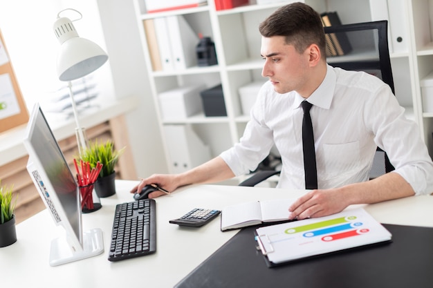 A young man sitting at a computer Desk in the office and working with documents.