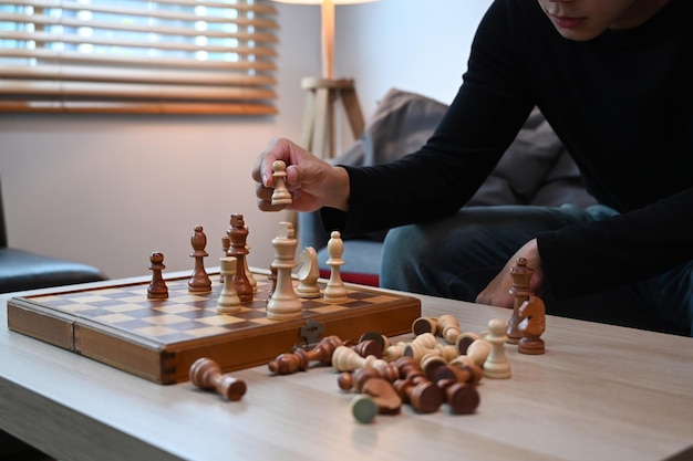 Молодой человек сидит на диване и играет в шахматы
