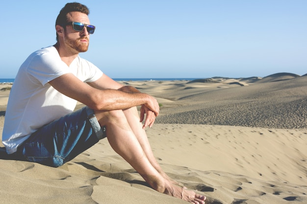 砂丘に座っている若い男
