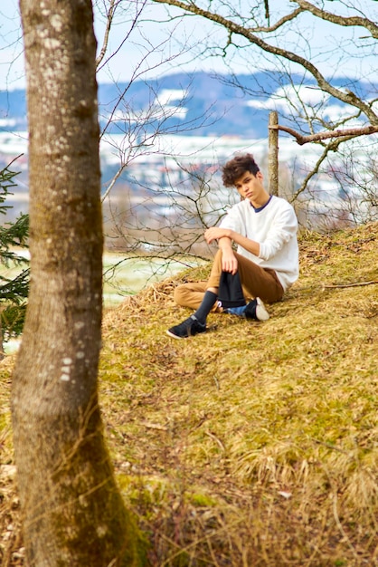 Photo young man sitting on field at forest