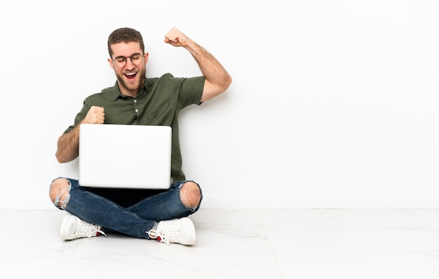 Young man sitting on the floor celebrating a victory