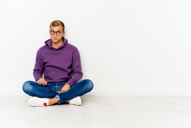 Young man sitting on the floor confused