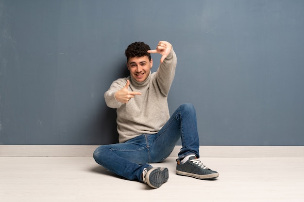 Young man sitting on the floor focusing face. Framing symbol