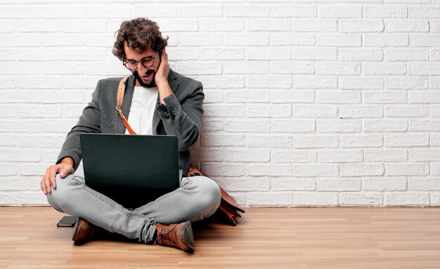 Young man sitting on the floor Laughing out loud 