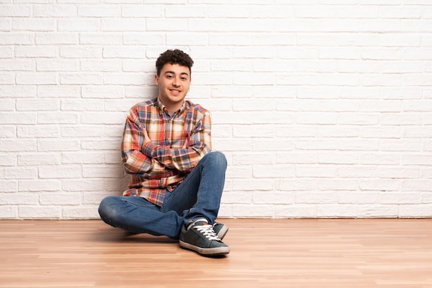 Young man sitting on the floor looking up while smiling