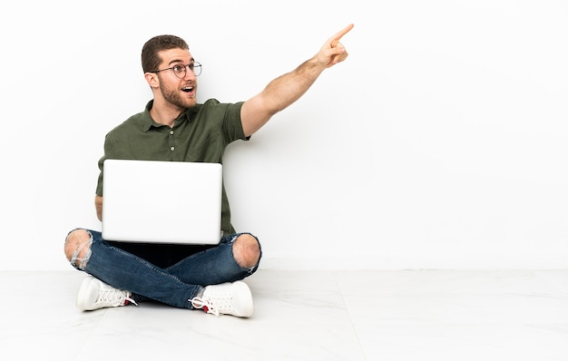 Young man sitting on the floor pointing away