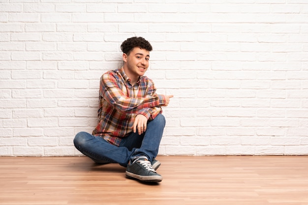 Young man sitting on the floor pointing back