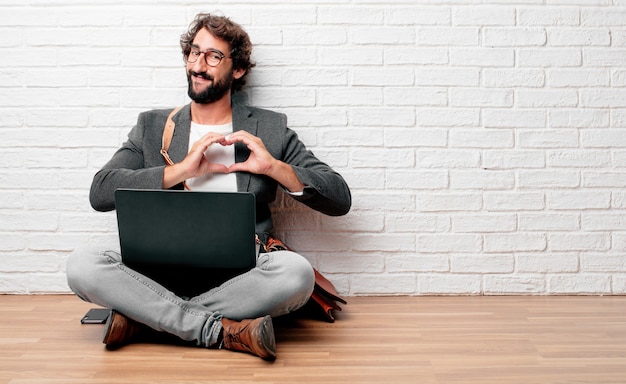 Young man sitting on the floor smiling, looking happy and in love