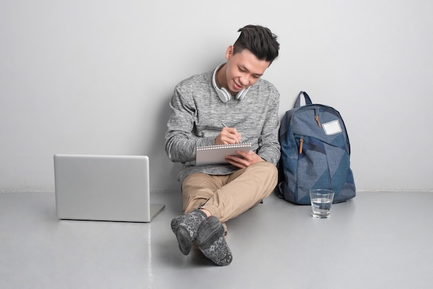 Young man sitting on the floor and using laptop.