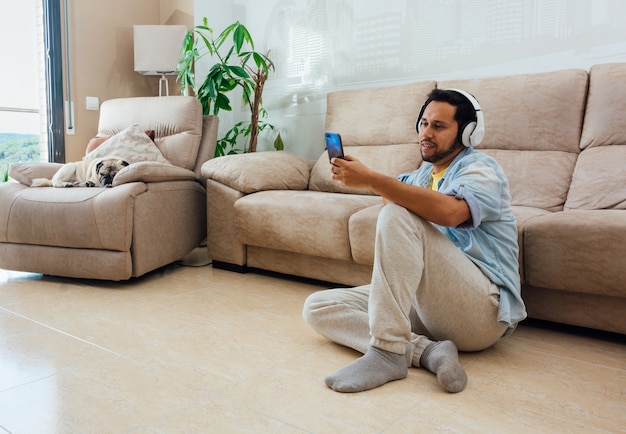 Young man sitting on the floor with phone and headphones