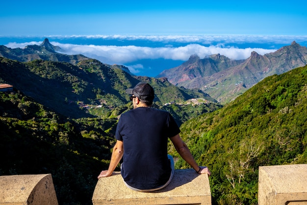 Giovane uomo seduto guardando le montagne di anaga nel nord di tenerife in spagna