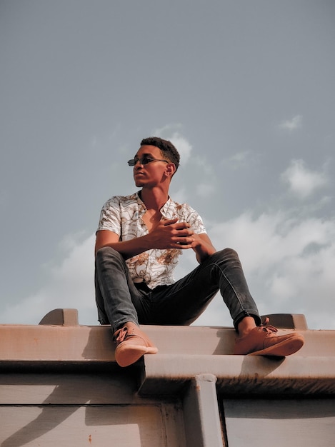 Photo young man sitting on looking away against sky