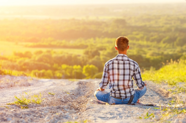 young man sitting in Lotus position with beautiful view at sunset