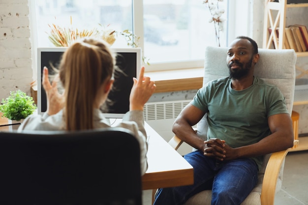 Young man sitting in office during the job interview with female employee, boss or HR-manager