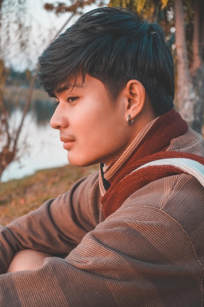 해가 지는 동안 야외에 앉아 있는 젊은 남자