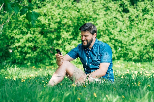 Young man sitting in the park and texting message