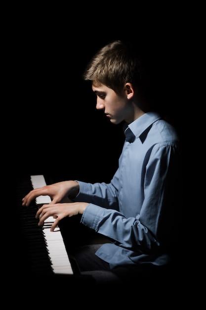 Giovane uomo seduto al pianoforte.