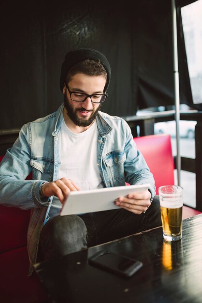 Young man sitting in a pub using tablet