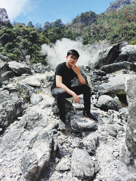 Photo young man sitting on rock