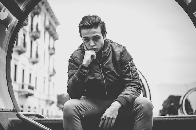 Photo young man sitting on sea at city street