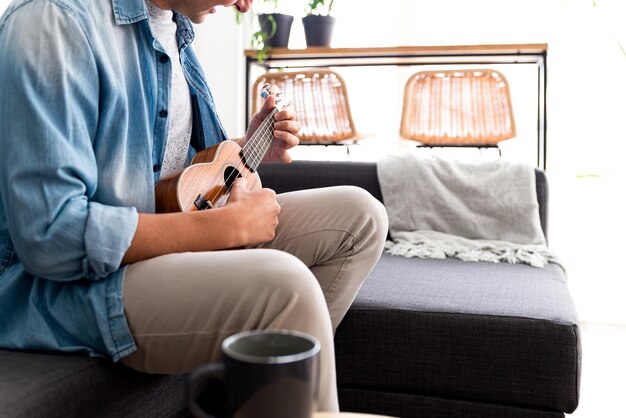 Young man sitting on a sofa playing the ukulele