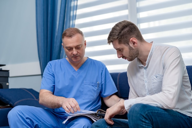 Giovane uomo seduto sul divano nella sala di ricevimento in ufficio. consultazione presso lo studio del medico.