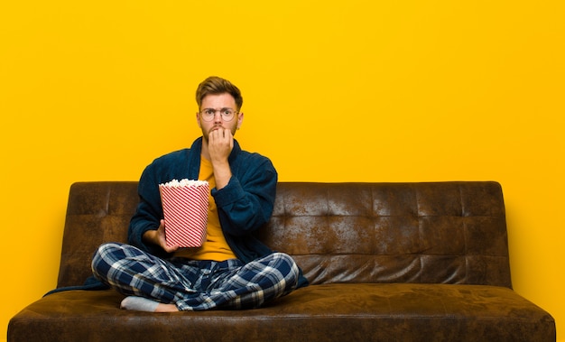 Young man sitting on a sofa with popcorns. cinema concept