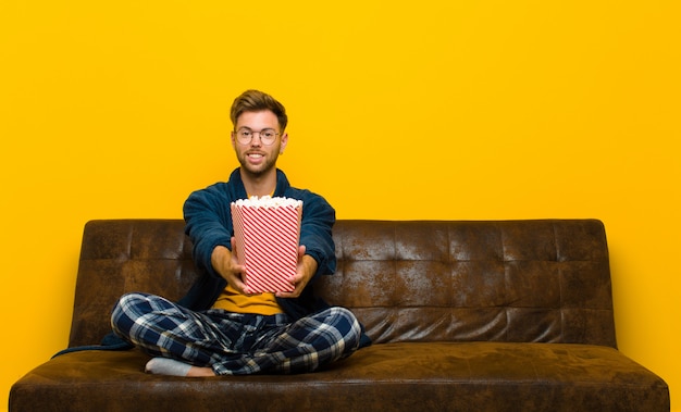 Young man sitting on a sofa with popcorns. cinema concept