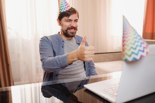 Young man sitting at the table and talking by video call to friends