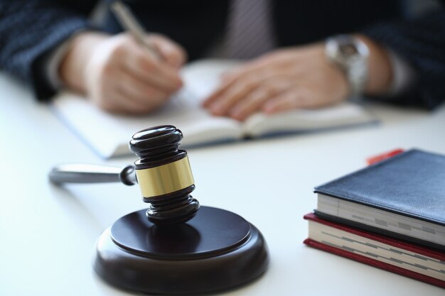 Young man sitting at the table with wooden handcrafted gavel