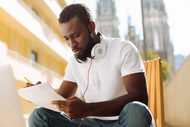 Young man sitting on a terrace and reading an article