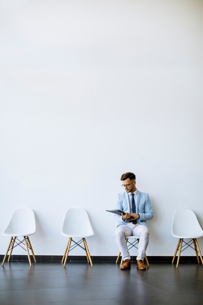 Young man sitting in the waiting room with a folder in hand before an interview