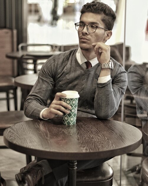 Photo young man sitting with coffee on table at cafe