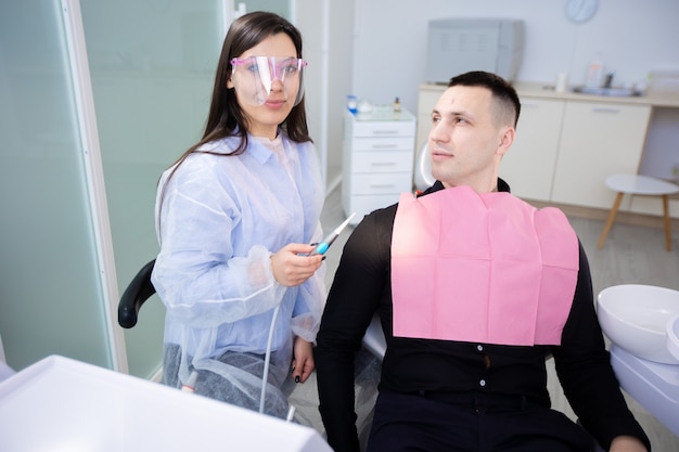 Foto giovane uomo seduto con dottoressa nell'ufficio del dentista