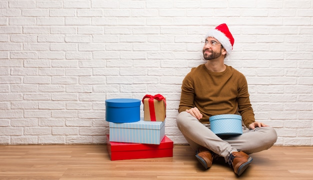 Young man sitting with gifts celebrating christmas dreaming of achieving goals and purposes