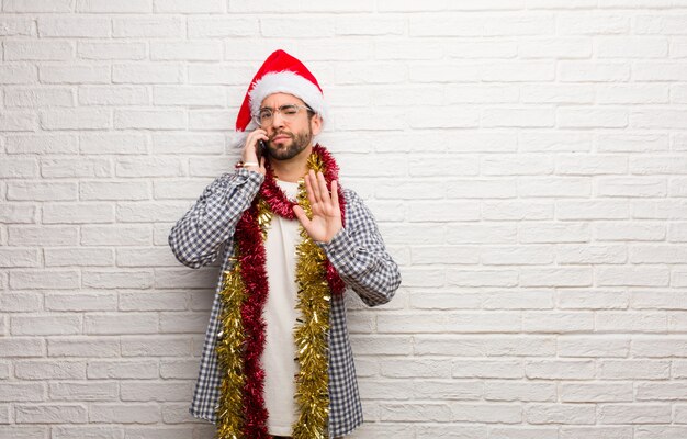 Young man sitting with gifts celebrating christmas putting hand in front