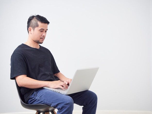 Lavoro di seduta del giovane con il computer portatile