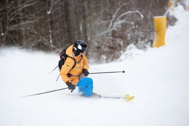 Young man skier in ski sportswear doing skillful maneuvers on skis. Skiing and turning on snow-covered mountain descent