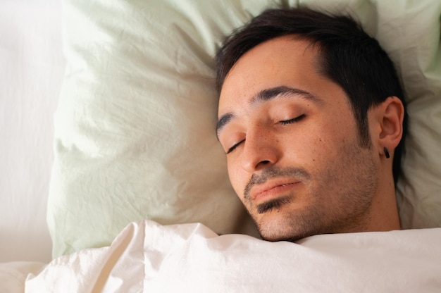 Photo young man sleeping on  bed